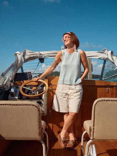 Person enjoying a sunny day on a boat, wearing casual summer attire, reflecting the relaxing theme of Laine Magazine Spring 28.