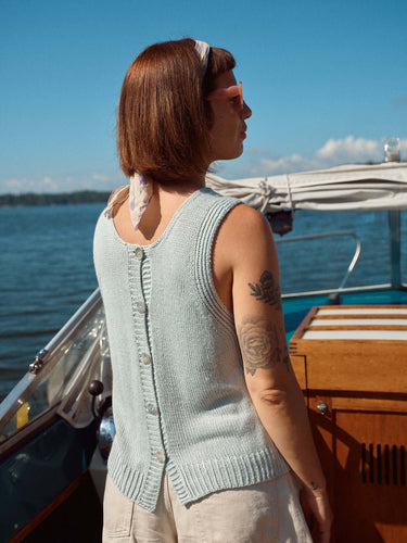 Woman wearing sleeveless knit top on a boat, promoting Laine Magazine Spring 28.