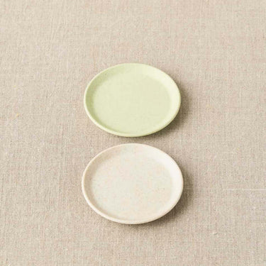 Two Cocoknits Magnetic Notions Dishes in green and beige, perfect for organizing small metal notion like stitch markers and needles.