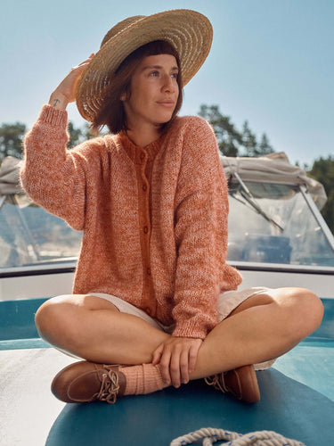 Woman in a knitted sweater and straw hat on a boat, featured in Laine Magazine Spring Issue 28.