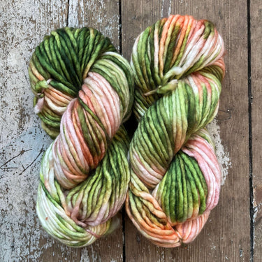 Three skeins of multicolored yarn on a wooden surface