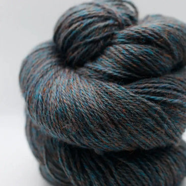 Close-up of Yarnadelic Sport yarn, rustic blend of Falklands Corriedale fibers, showcasing rich tones of blue and brown.