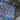 Knitted blanket with floral pattern on a stone surface with pink flowers and green leaves.