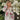Woman wearing a patterned sweater standing among white flowers