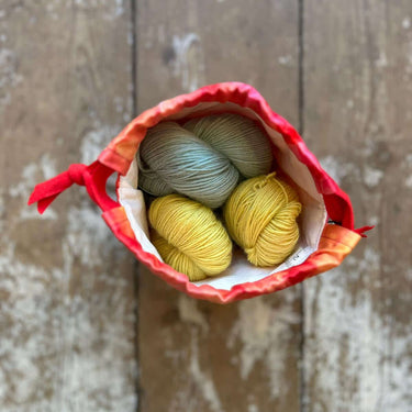 Top view of a small Ice Dyed Project Knitting Bag holding colorful yarn balls, showcasing its unique design and craft-friendly features.