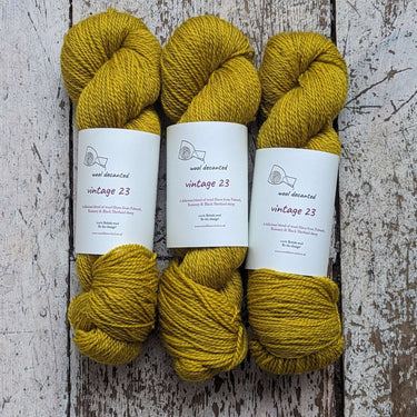 Wool Decanted Vintage 23 4ply Yarn skeins in mustard yellow on rustic wood background