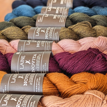 Laine x Novita DK yarn showing various color skeins in a row, highlighting high-quality Falkland wool and Bluefaced Leicester blend.
