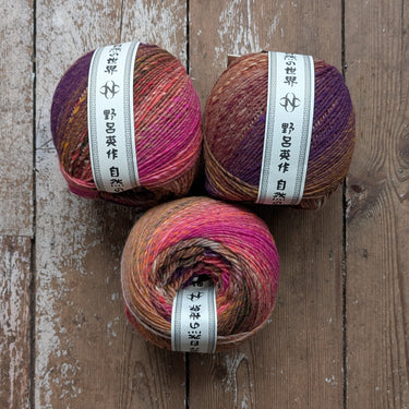 Colourful Noro Ito worsted weight yarn balls showcasing diverse patterns on wooden floor.