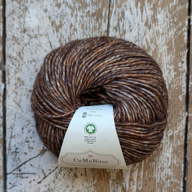 Brown yarn skein with a label on a wooden surface