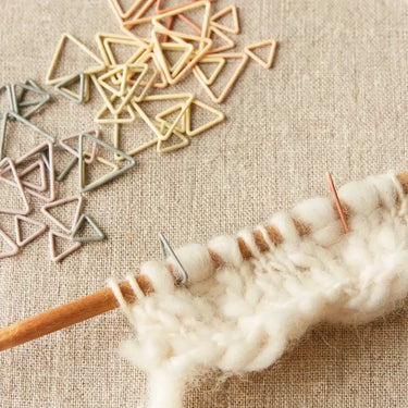 Triangle Stitch Markers by Cocoknits in earth tones used in knitting on beige fabric