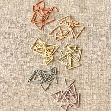 Triangle Stitch Markers by Cocoknits in earth tone colors on a beige background.