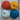 Four balls of yarn in orange, yellow, light blue, and dark blue on a wooden background, perfect for crochet projects.