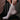 Person wearing a textured pink sock on a wooden chair.