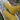 Mustard yellow knitted socks on a wooden log with greenery in the background