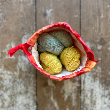 Top view of a small Ice Dyed Project Knitting Bag holding colorful yarn balls, showcasing its unique design and craft-friendly features.