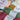 Yarns for Marie Wallin Hot Water Bottle Cover Kit, featuring Fairisle knitting and crochet details with pom pom or flower decorations.