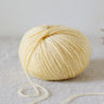Ball of Alice | De Rerum Natura yarn, 75% organic merino, 25% linen, elastic and soft with a luminous finish, resting on fabric surface.