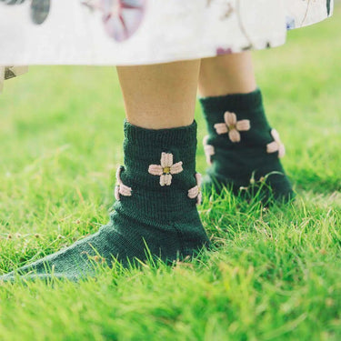 Green socks with floral patterns from Amirisu Sock Knitting Club on grass