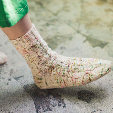 Colorful patterned sock from Amirisu Sock Knitting Club showcased on foot.