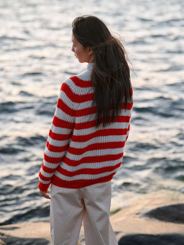 Model wearing striped knitwear from Art of the Sea collection by Laine, inspired by the Moomins, standing by the ocean.