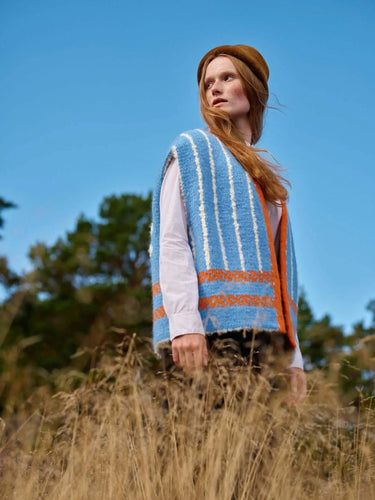 Art of the Sea knitwear design inspired by the Moomins, featuring a model in a blue and orange striped vest in a natural setting.