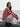 Woman wearing striped knit sweater from Art of the Sea - 23 Knitwear Designs Inspired by the Moonins by Laine, sitting by the sea.