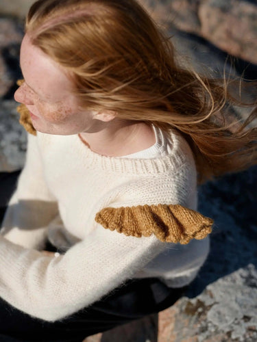Art of the Sea knitwear design inspired by the Moomins, featuring a model wearing a white sweater with textured shoulder details.