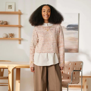 Person wearing a sweater in a modern interior, promoting 'Beaded Colourwork: A Modern Approach to Knitting with Beads by Jeanette Sloan'