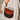 Brown leather half-moon handbag with beaded detailing held by model in beige shirt.