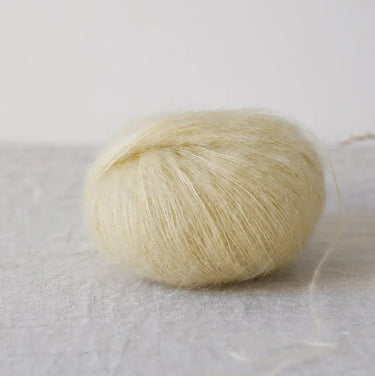 Bérénice lace weight yarn with Angora goat fibers and organic Merinos, eco-dyed, soft and voluminous on a linen surface.