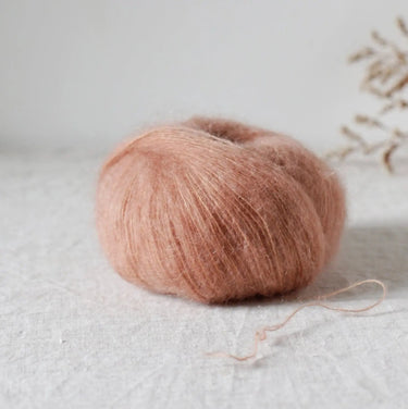 Bérénice lace weight yarn with extra-fine Angora and organic Merinos d'Arles on a textured background, focusing on sustainability.