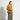 Woman holding a brown handbag wearing a mustard yellow sweater and green pants on a white background