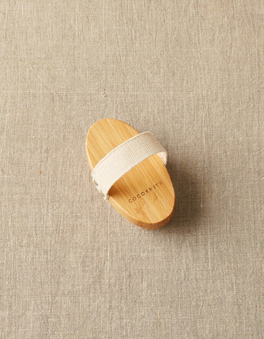 Cocoknits Sweater Care Brush with natural boar bristles for depilling and rejuvenating textiles, shown on a beige background.