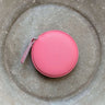 Pink Colourful Tape Measure in round case on textured surface