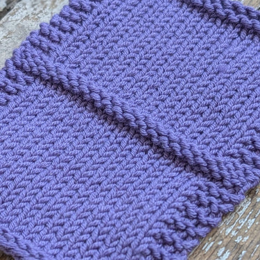 Purple knitted swatch of CottonWool 5 by Gepard on a wooden surface