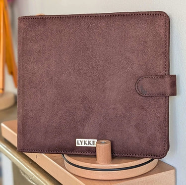 Brown case for CYPRA COPPER DOUBLE POINTED NEEDLE SET by LYKKE, displayed on a wooden stand.