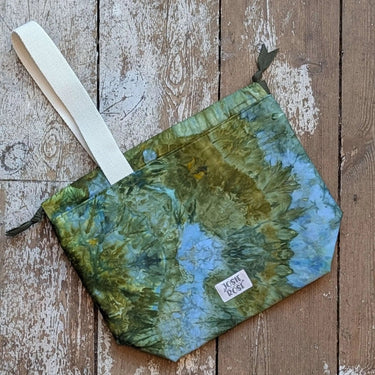 Large ice dyed craft project bag in green and blue tones with white handle, featuring a unique Jose Rose design on wooden floor.