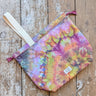 Ice Dyed Project Bags - XLarge shown on wooden floor, multicolored tie-dye effect, Jose Rose brand, with strap and zipper closure.
