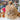Large Natural Monsterfluff Stuffed Alpaca in store with colorful yarn background and floral decor