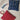 Two woven pouches, one red and one blue, on a marble surface.