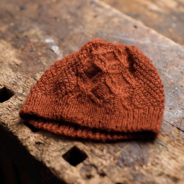 Brown knitted hat on a textured stone surface