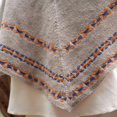 Close-up of a textured fabric with orange and blue stitching on a blurred background