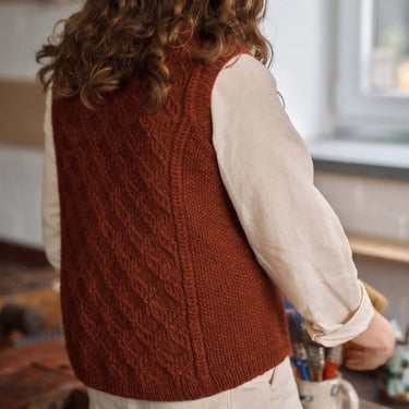 Person wearing a brown knitted vest in a kitchen setting