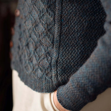 Close-up of a person wearing a blue knitted sweater with intricate patterns.
