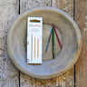 KnitPro Dreamz wood cable needles with smooth tips and grooves, displayed with packaging on rustic surface for knitting projects.