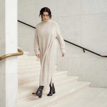 Woman in a long knit dress walking down stairs, showcasing winter fashion from Laine Magazine Issue 27.