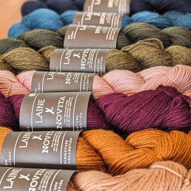 Laine x Novita DK yarn showing various color skeins in a row, highlighting high-quality Falkland wool and Bluefaced Leicester blend.
