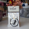 LYKKE Interchangeable Cords in packaging on a display with yarn background.