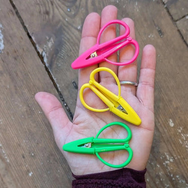 Mini Scissors with silicone cover in pink, yellow, and green, shown on a hand. Compact 2.5-inch design, perfect for travel.