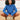 Person wearing blue crocheted sweater holding a patterned bag. Showcasing design from Hooks Out! by Molla Mills.